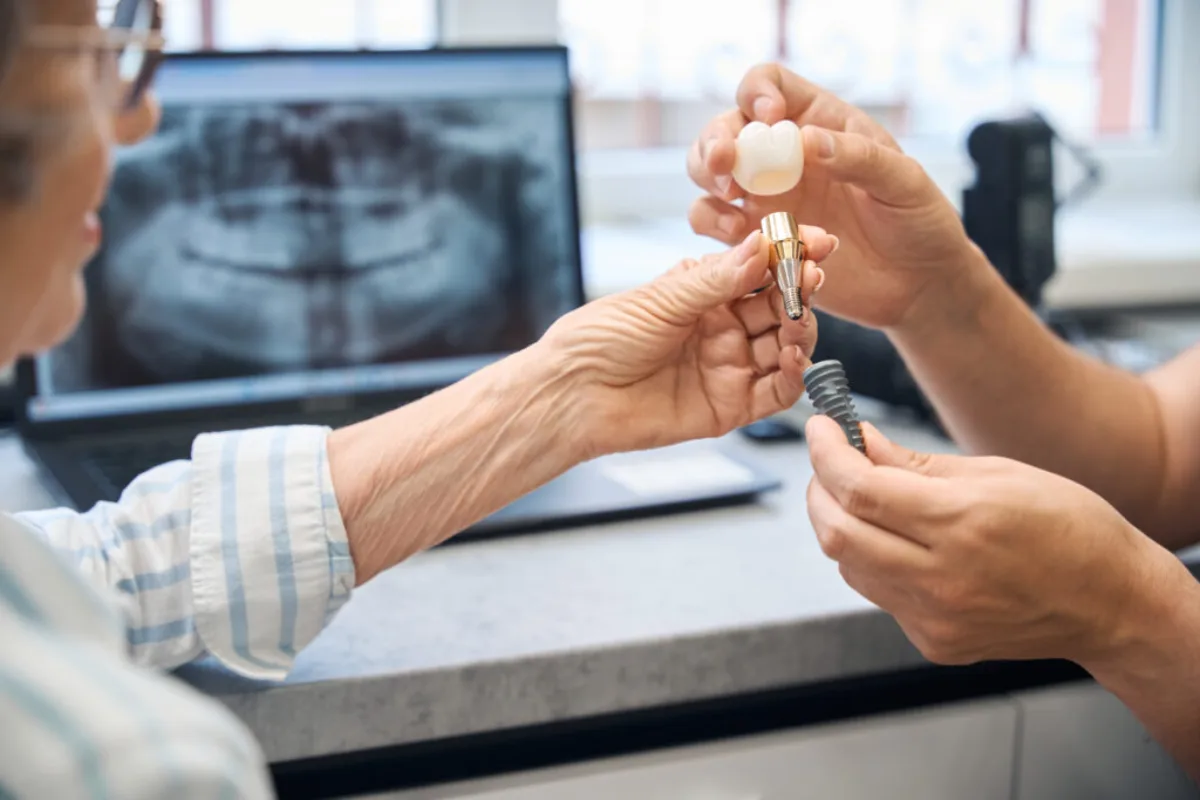 Röntgen görüntüsü önünde implant modelini inceleyen hekimler